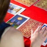 Fortune teller using tarot cards on red table