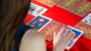 Fortune teller using tarot cards on red table
